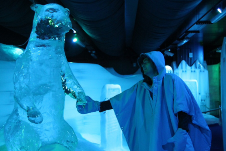 أحد زوار متحف الثلج يرتدي لبس الاسكيمو ويلتقط صورة لنفسه